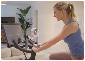 Woman staying cool with Arctic Air® Grip Go™ attached to her exercise bike